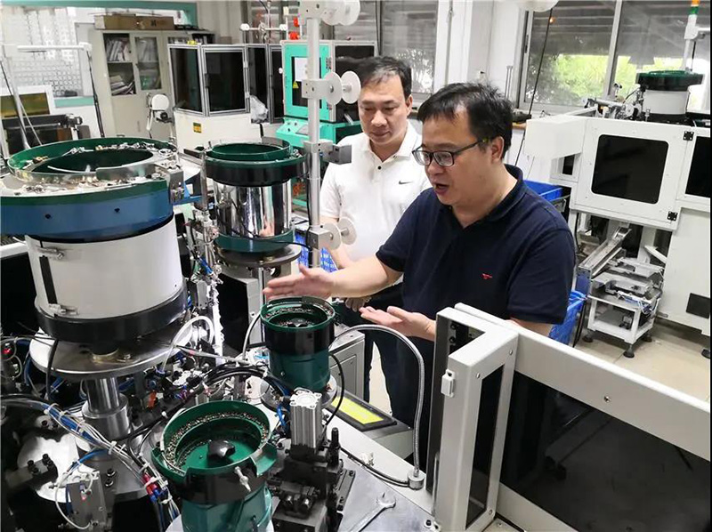 華圣達技術(shù)設(shè)備中心研發(fā)人員（右）在介紹自主研發(fā)的智能生產(chǎn)拉鏈機械設(shè)備